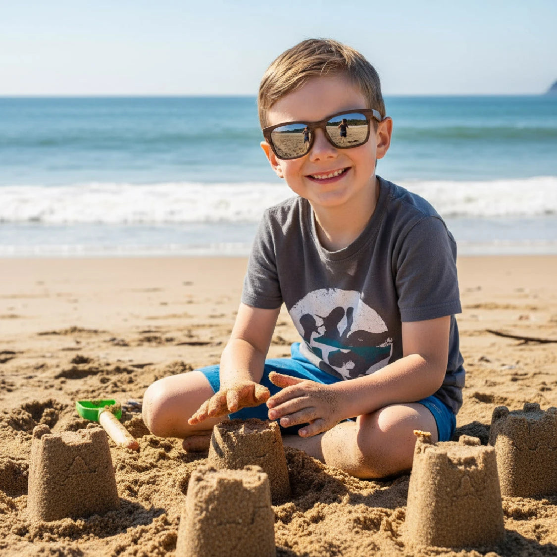Child building sandcastles on a beach with Madeira sunglasses