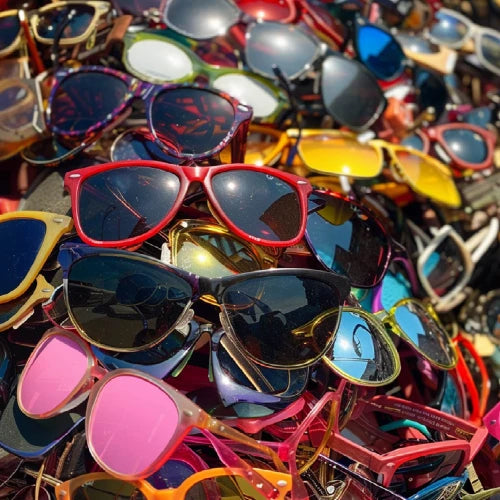 Pile of colorful sunglasses with various designs and colors.