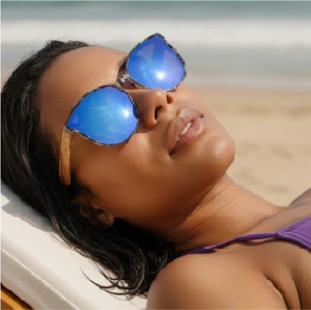 Woman lying in the sun on a beach wearing Wildwood sunglasses and smiling