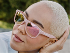 Person wearing pink sunglasses with a blurred natural background