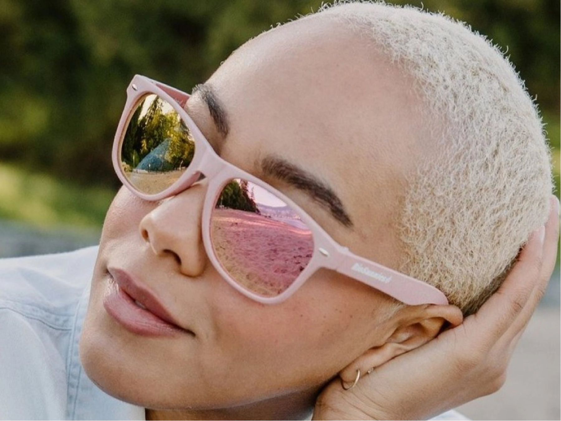 Person wearing pink sunglasses with a blurred natural background