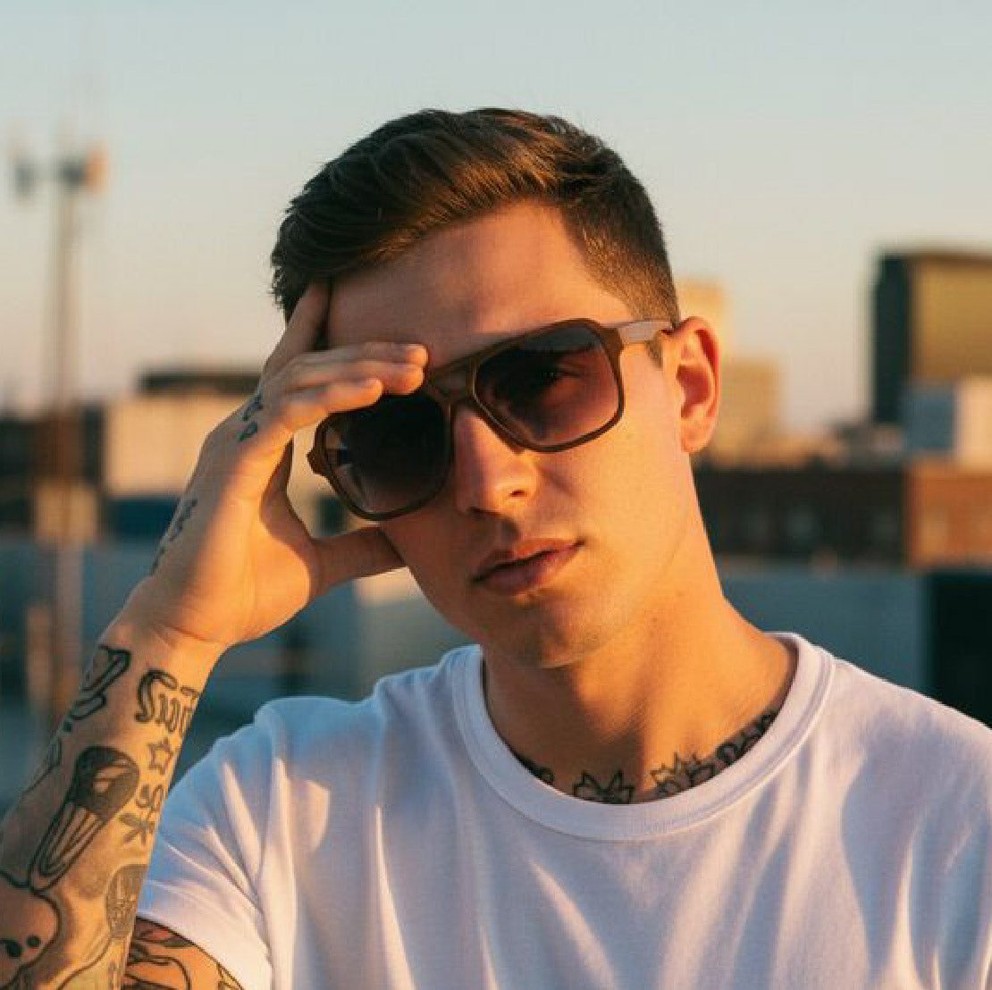 Man wearing sunglasses with a blurred cityscape background