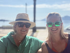 Two people wearing sunglasses and hats outdoors with a clear sky.