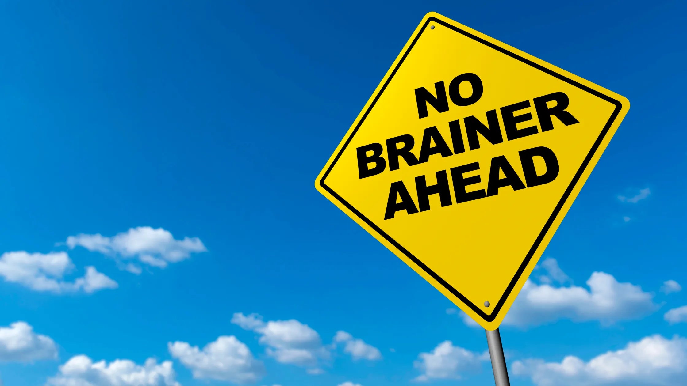 Yellow road sign with 'No Brainer Ahead' text against a blue sky
