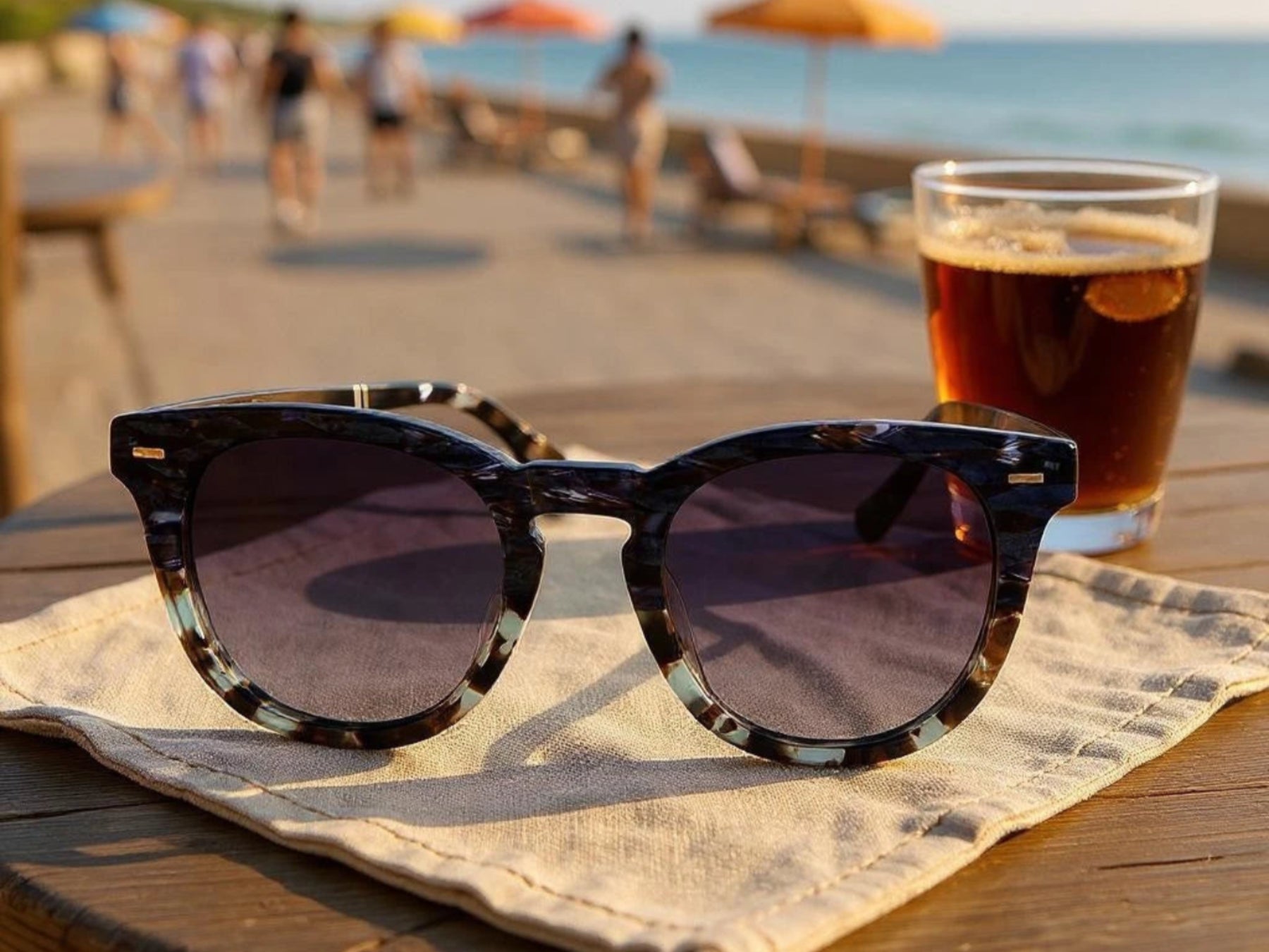 Sunglasses and a glass of beer on a table with a beach background