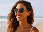 Woman wearing sunglasses on a beach with a clear sky