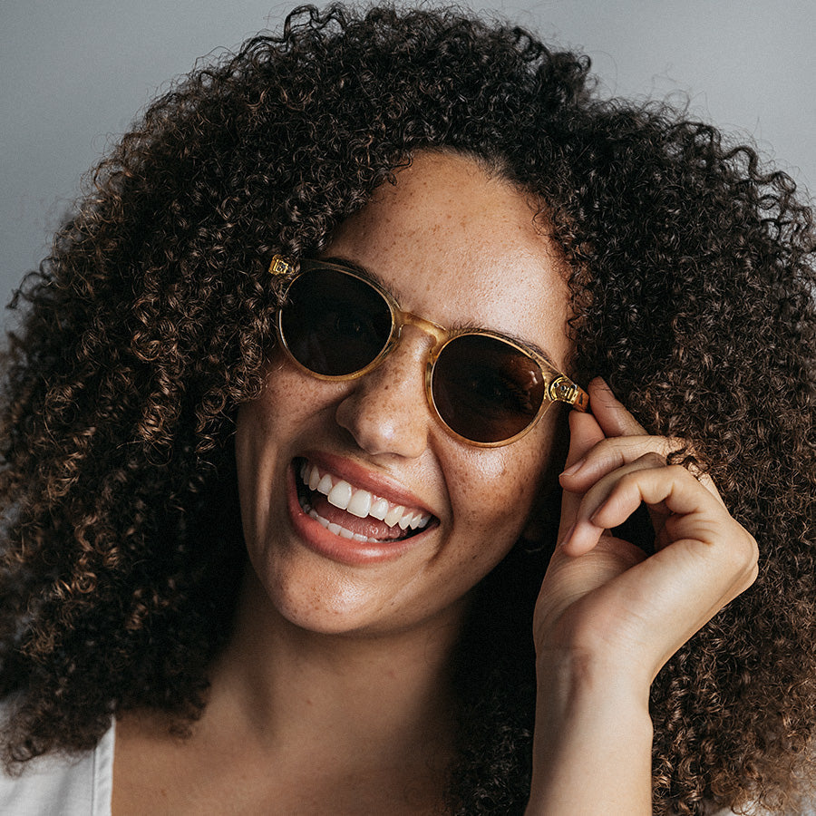 Black woman wearing round yellow frame sunglasses